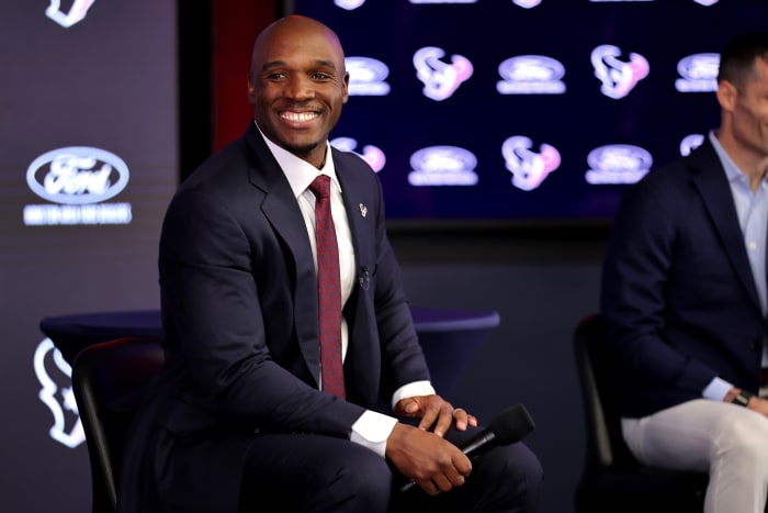 DeMeco Ryans smiles looking over his shoulder as he holds a mic down by his lap